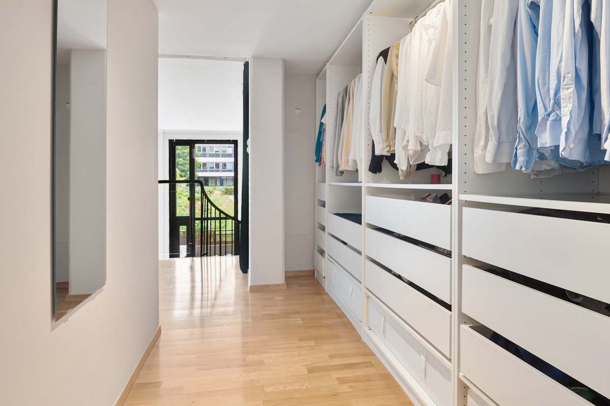 Closet planejado claro com gavetas e cabideiros